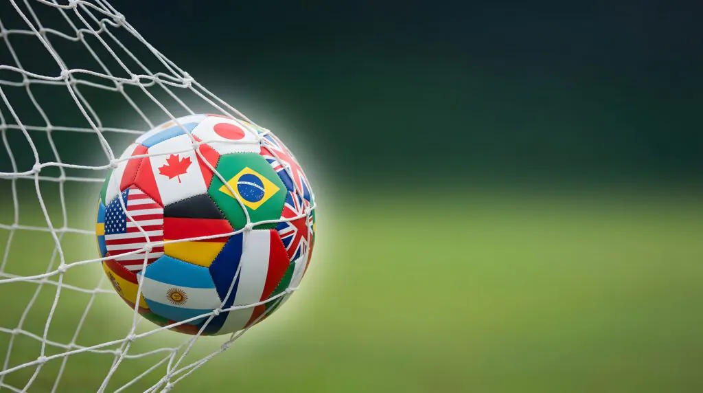 Soccer ball decorated with international flags caught in a goal net, symbolizing the FIFA World Cup and global competition.